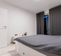 A bedroom with white furniture, gray curtains, and a bed in a two-room apartment.