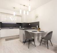 A kitchen in a 2-room apartment with white cabinets and a wooden decor floor.