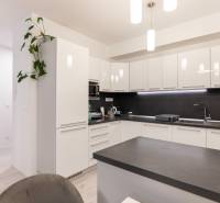 A kitchen unit with white cabinets and a black countertop in a two-room apartment.