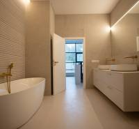 A bathroom with a freestanding bathtub, gold details, and a double sink in a 4-room apartment.