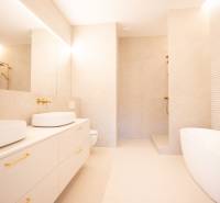 A spacious bathroom with golden elements, two sinks, and a freestanding bathtub in a 4-room apartment.