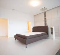 Bedroom of a 4-room apartment with a dark headboard and built-in wardrobes.