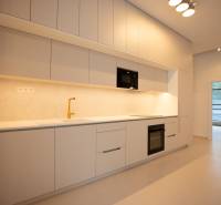 A kitchen in a 4-room apartment with white cabinets, a gold faucet, and built-in appliances.