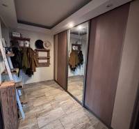 A hallway with a wooden decor floor, a built-in wardrobe, and a coat rack in a 2-room apartment.
