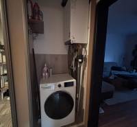 Washing machine and boiler located in the storage space of a 2-room apartment with tiles.