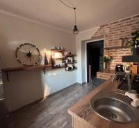A kitchen in a 2-room apartment with a gray floor and brick cladding.