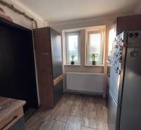 A kitchen in a 2-room apartment with a wood-patterned floor and modern furnishings.