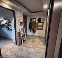 A hallway in a 2-room apartment with a coat rack, shelves, and tiles with a wooden design.