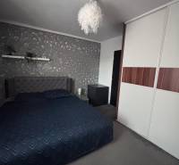 Bedroom in a 2-room apartment with a bed, wallpaper, and a wardrobe.