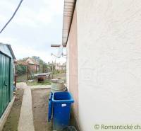 The courtyard of the family house in Ľudovítová with a metal shelter and a blue waste container.