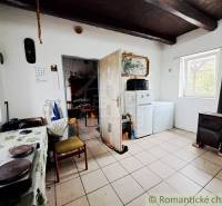 A kitchen in a family house with a stove and a refrigerator, the floor is light tiles.