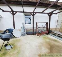 The garden of the family house in Ľudovítová with a pergola, grill, and building materials.