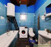 A bathroom in a family house with blue tiles, a bathtub, a sink, and a washing machine.