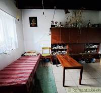 A simple room in a family house with a bed, carpets, and an open wardrobe.