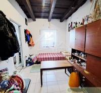 Interior of a family house with a wooden ceiling, furniture, bed, and clothes on the wall.