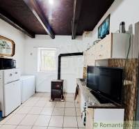 A kitchen in a family house with a stove, refrigerator, kitchen unit, and television.