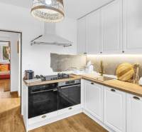 A kitchen in a family house with a wooden decor floor and a view into the living room.