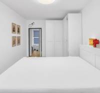 A bedroom in a family house with white walls, a built-in wardrobe, and simple decor.