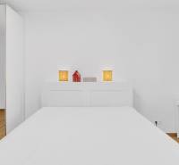 A bedroom with white walls in a family house, a bed, a table, and a floor with a wooden decor.