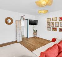 Living room with a red sofa, paintings on the wall, and a wooden decor floor in a family house.