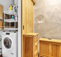 A bathroom in a family house with wooden furniture, a washing machine, and storage shelves.