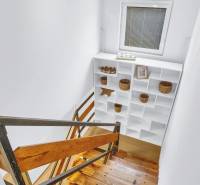 A staircase with a wooden floor leads to white shelving units in a family house.