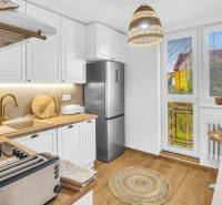 The kitchen of a family house with white cabinets, wood-patterned flooring, and a stainless steel appliance.