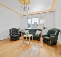 Living room with a leather sofa and armchairs, wooden floor, chandelier, 3-room apartment.