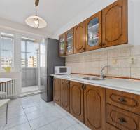 A kitchen with a wooden cabinet and appliances in a 3-room apartment with access to a balcony.