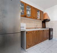 A kitchen in a 3-room apartment with wooden cabinets, a microwave, and a stainless steel refrigerator.