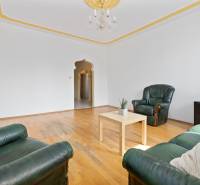 Living room in a three-room apartment with green sofas and wooden flooring.