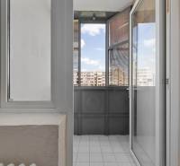 A balcony in a 3-room apartment with tiles and a view of the apartment blocks.
