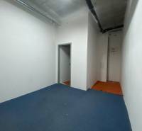 Commercial space with blue carpet, white walls, and piping on the ceiling.