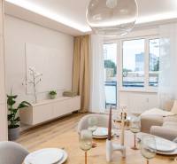 Living room of a 4-room apartment with a large window, beige sofa, and dining table.