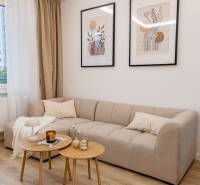 Living room in a 4-room apartment with a beige sofa and wooden floor decor.