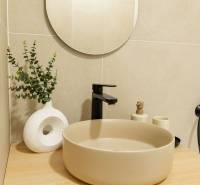Bathroom in a 4-room apartment with a round sink, mirror, and decorative accessories.