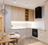 A kitchen in a 4-room apartment with white cabinets, wooden cupboards, and a small dining table.