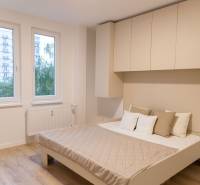 Bedroom in a 4-room apartment with a wooden decor floor and built-in wardrobes.