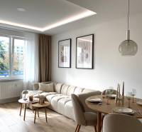 Living room of a 4-room apartment with a sofa, dining table, and wooden-patterned flooring.