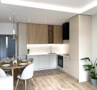 Modern kitchen with a dining table, wood-patterned flooring, and white tiles.