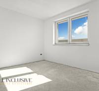 An empty room in a family house with white walls and a large window.
