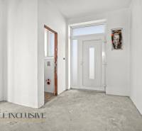 Entrance hallway in a family house with white walls and an incomplete floor.