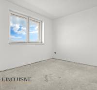 A spacious room in a family house with white walls and a window overlooking the sky.
