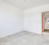 The interior of a family house with white walls and a hallway leading to another room.