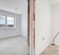 An empty room with a large window and unpainted walls in a family house.