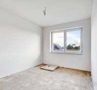 An empty room with white walls and a window, floor ready for finishing.