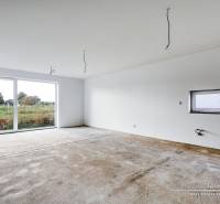 A spacious room in a family house with a large window and a concrete floor.