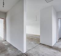 A hallway in an unfinished family house with a concrete floor and white walls.