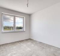 An empty room in a family house without flooring, with a large window and white walls.