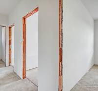 Interior of a family house with white walls and wooden door frames without flooring.